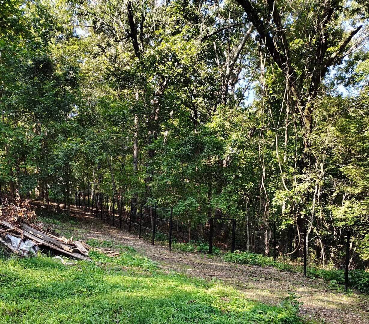 3D welded wire fence line following a wooded property boundary